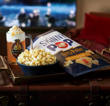 Popcorn, mug of beer, and 'Skinny Pop' bag on a table 