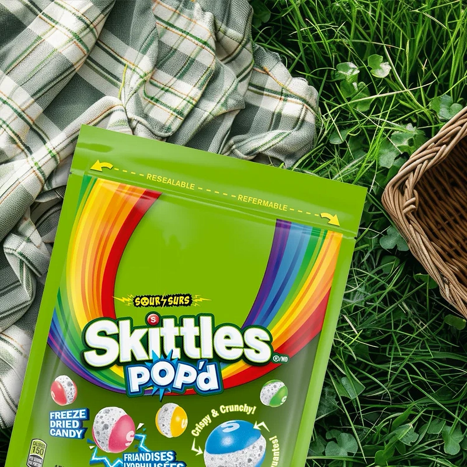 Skittles Pop'd candy package on grass with plaid blanket and basket