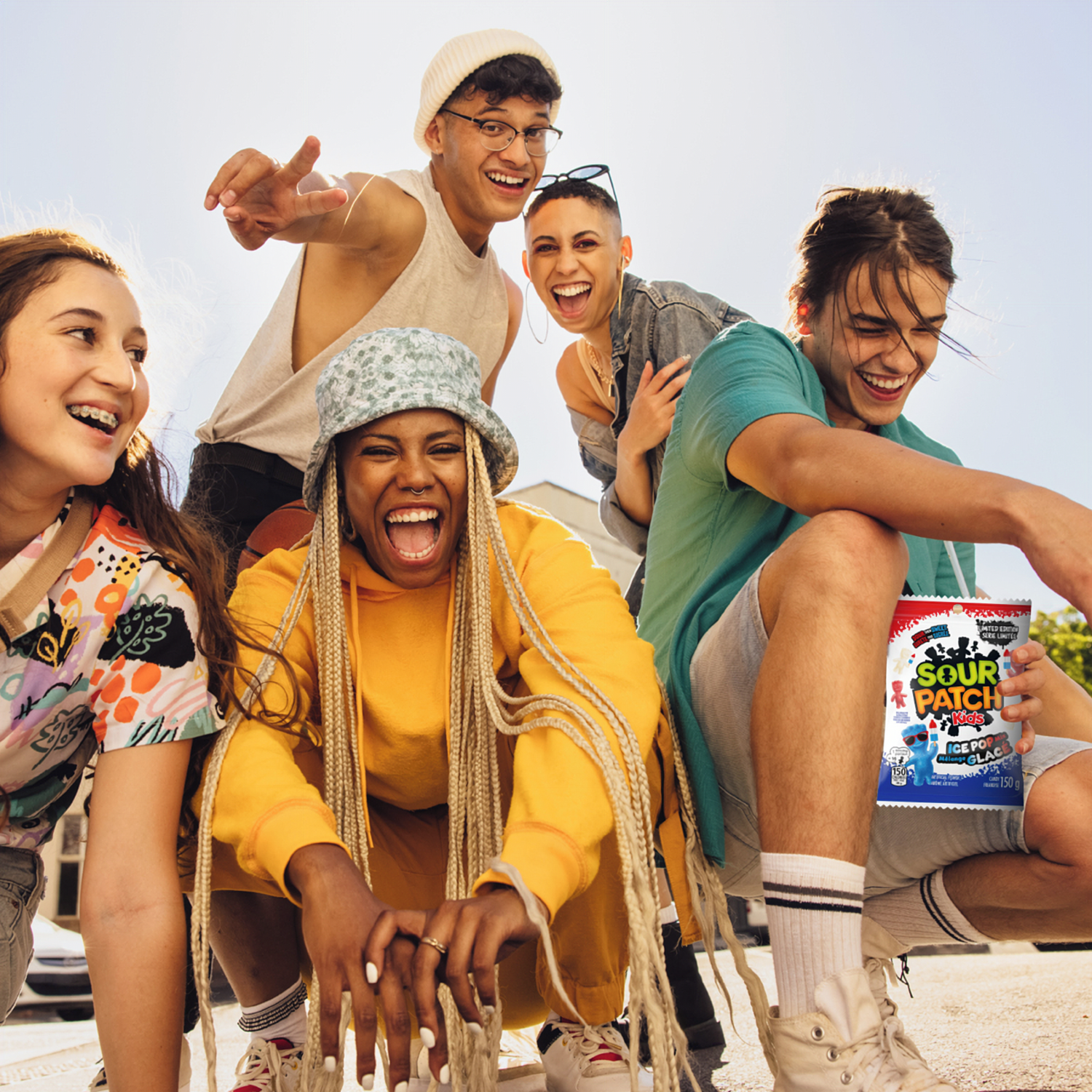 Group of young people posing outdoors with a 'Sour Patch' product.