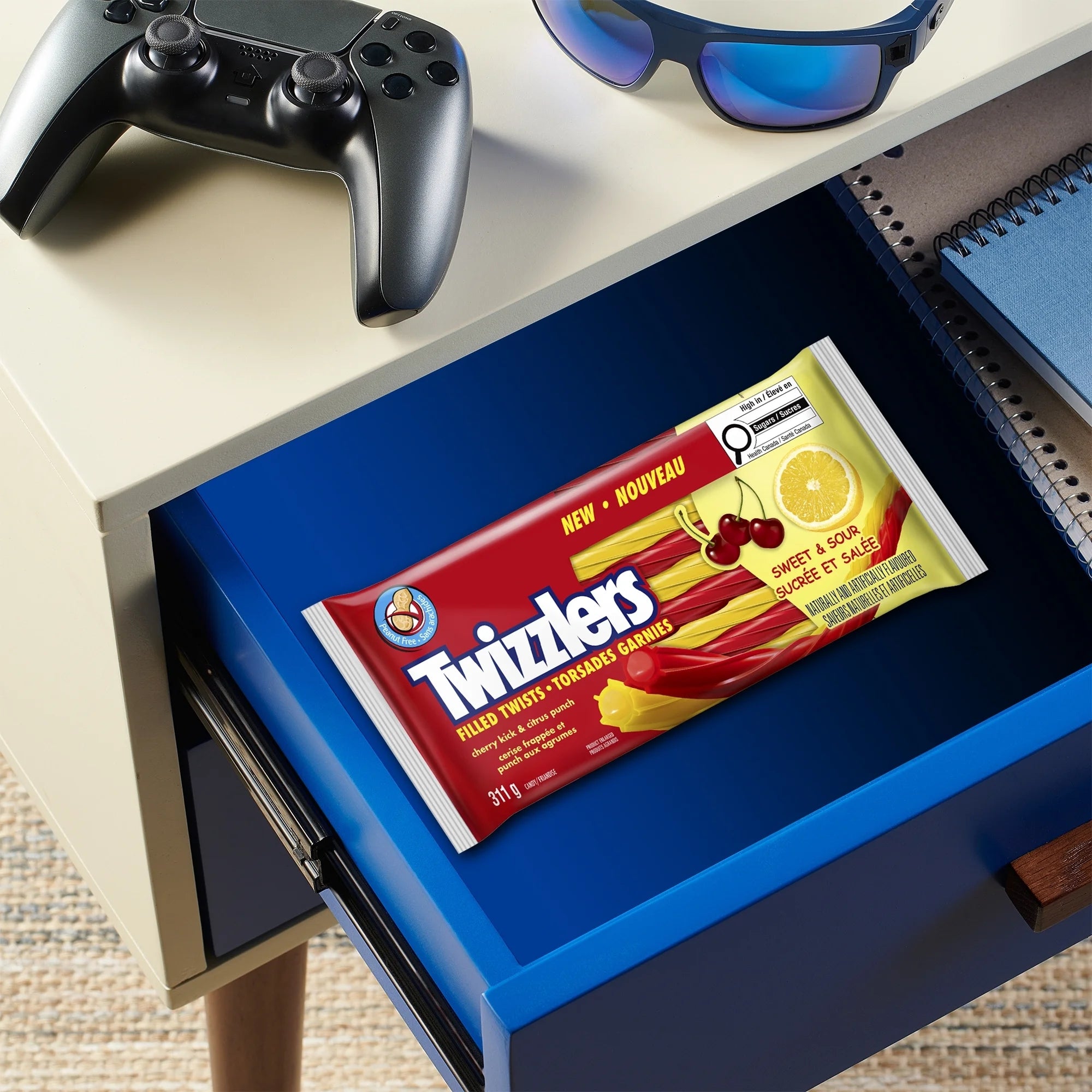 Twizzlers candy package on a blue drawer with sunglasses and a gaming controller above.