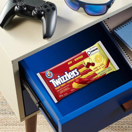 Twizzlers candy package on a blue drawer with sunglasses and a gaming controller above.