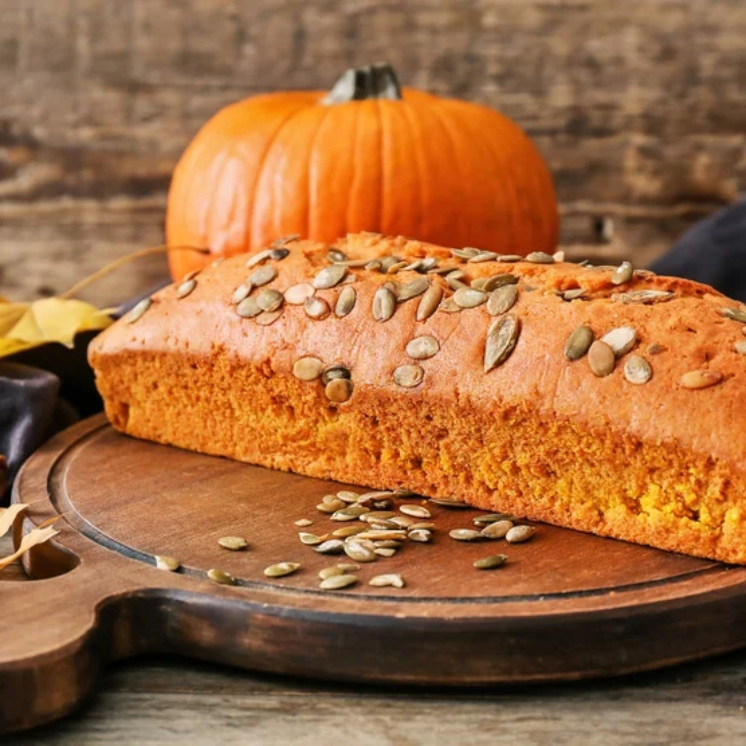 Pumpkin seed loaf topped with Yupik raw shelled pepitas on a wooden board — baking with pumpkin seeds