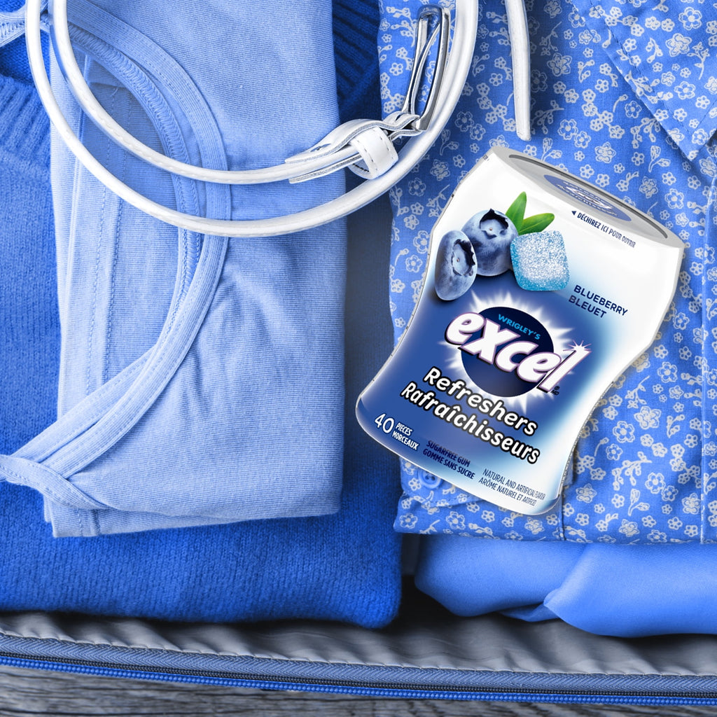 Excel Sugar-Free um, Refresher Blueberry, 6 ct. Package, one bottle on clothes in suit case.