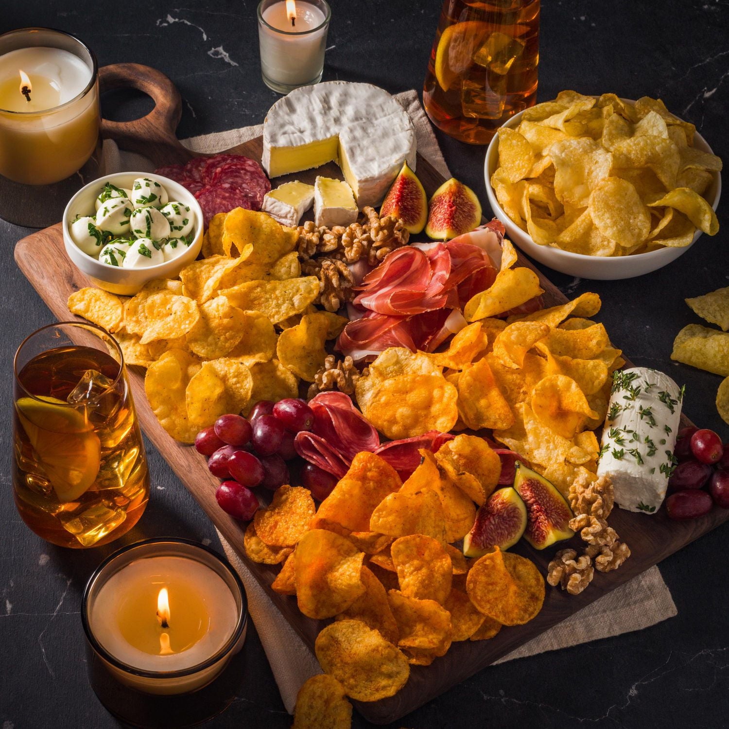 Compliments Kettle-Cooked Black Pepper & Lime Potato Chips on a charcuterie board.