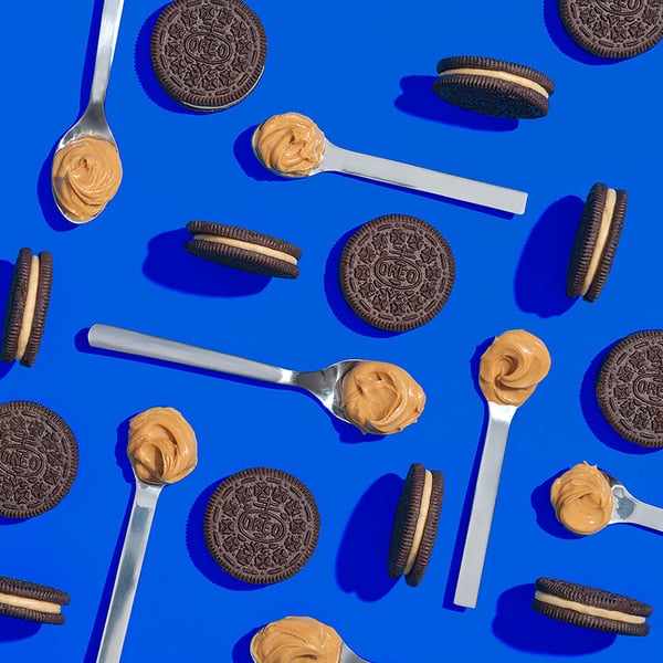 Cookies and peanut butter on spoons against a blue background