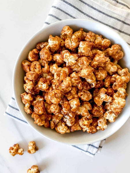 White bowl filled with Compliments Spicy Maple Flavored Popcorn Mix, Sweet & Spicy Popcorn Snack 200g/7.1 oz on a white surface with a striped cloth.