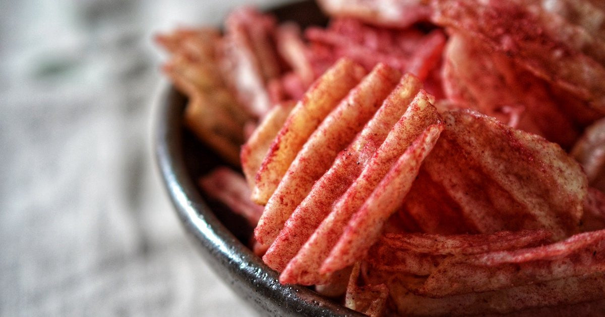 Compliments Extraaa Ketchup Flavor Ridged Potato Chips in a bowl.